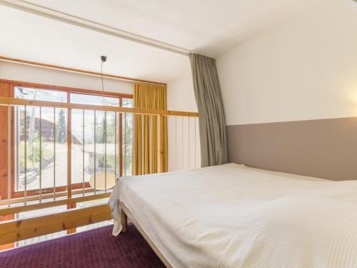 une chambre avec un lit et une grande fenêtre dans l'établissement Duplex confort au pied des pistes avec balcon, parking et WiFi gratuits - Arc 1800 - FR-1-346-380, à Arc 1800