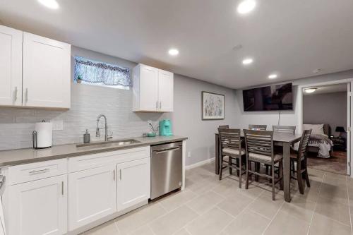 Una cocina con gabinetes blancos y una mesa y sillas. en Bright basement unit with large yard and sunroom, en Denver