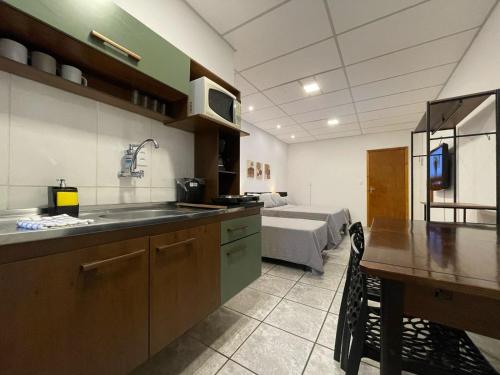 a kitchen with a sink and a bed in a room at Villa Bilac - Amplos Studios 2km da Vila Germânica in Blumenau