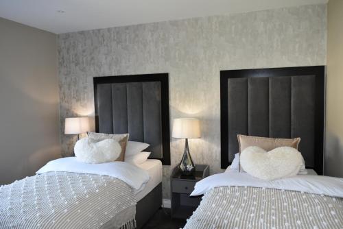 a bedroom with two beds with white pillows at Muckross Luxury Residences in Killarney