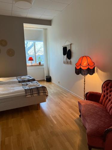 a bedroom with a bed and a chair and a lamp at Rindö Hamn Bed & Breakfast in Vaxholm