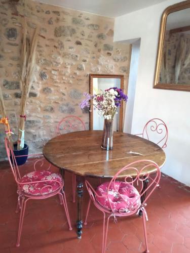 une table avec des chaises roses et un vase de fleurs dans l'établissement Charmante maison avec piscine proche de la mer, à Sorède