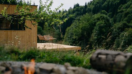 a wooden bench sitting in front of a forest at Domček Lazy in Lazy pod Makytou