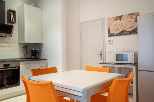 a kitchen with a white table and orange chairs at lachiocciola - Centro storico di Imola, autodromo e Formula 1 in Imola