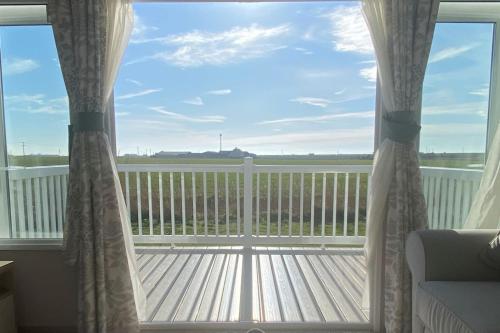 a view of a deck from a window with curtains at MP724 - Parkdean Camber Sands in Camber