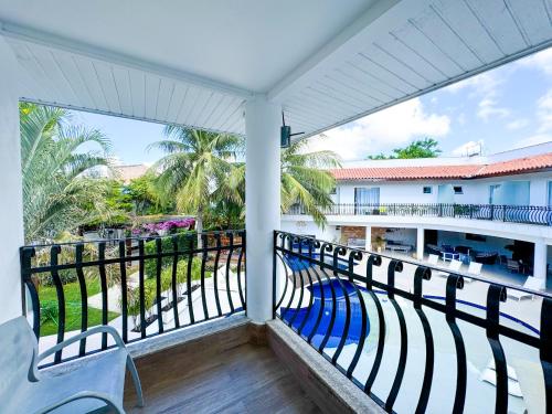 a balcony with a view of a pool and palm trees at Hotel Boutique Recanto da Passagem in Cabo Frio