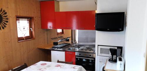 - une cuisine avec des placards rouges, un évier et une cuisinière dans l'établissement Résidence La Croix Du Sud - Studio cabine 4 personnes 2 exposé nord MAE-7924, à Valloire