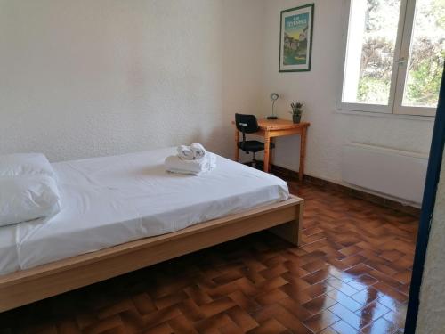 una camera da letto con un letto, una scrivania e una finestra di Gîte les iris Laroque 34 DOUBLON a Laroque