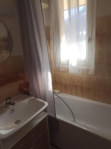 La salle de bains est pourvue d'un lavabo, d'une baignoire et d'une fenêtre. dans l'établissement Appartement cosy 4 couchages -Pont du Verdon- centre station, à La Foux