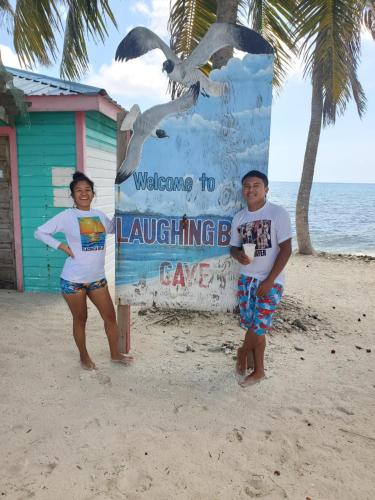 two people standing next to a sign on the beach at Maya Beach Hotel in Maya Beach