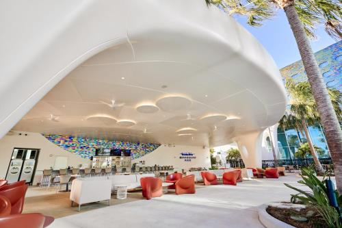 a large white building with chairs and tables and palm trees at Universal's Terra Luna Resort in Orlando