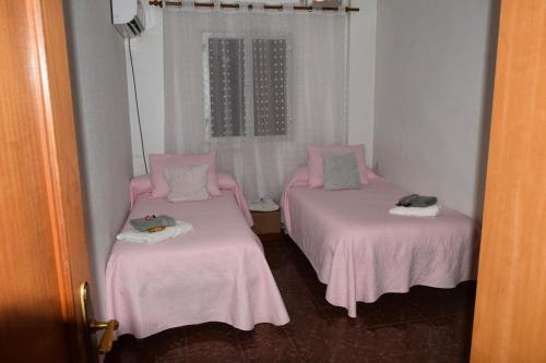 two beds in a room with pink sheets at Casa Rural Chalet Venta del Aire Cortijo Terron in Lanjarón