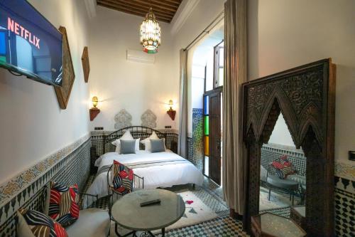 a bedroom with a bed and a table and a tv at Riad Fes la Mama - Rooftop in Fez