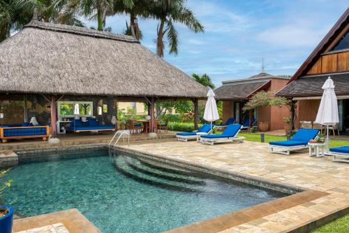 a swimming pool with blue chairs and a house at Villa Ebony -Tropical Design with Ocean Views, 5-star resort in Albion