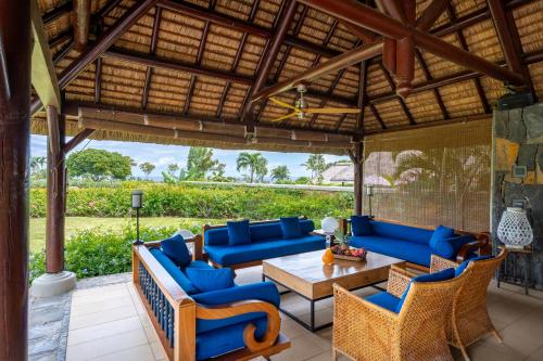 an outdoor patio with blue couches and a table and chairs at Villa Ebony -Tropical Design with Ocean Views, 5-star resort in Albion