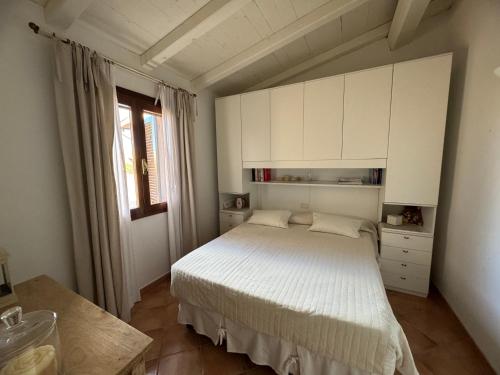 a bedroom with a bed with white cabinets and a window at Villa Carlotta in San Teodoro