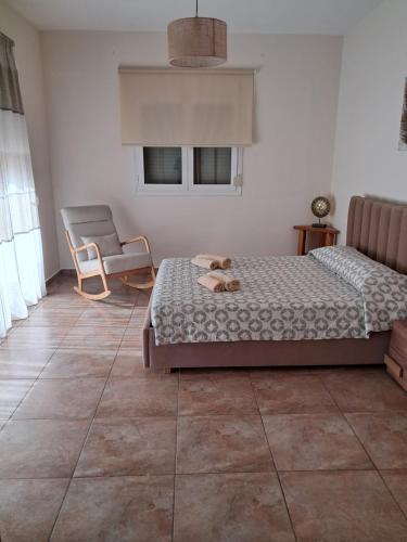a bedroom with a bed and a chair and two windows at ILIANA.APARTMENTS in Kardamaina