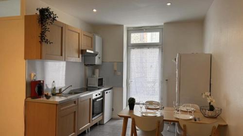 une cuisine avec une table et un réfrigérateur dans l'établissement Le St Antoine Central - Gare, à Mâcon