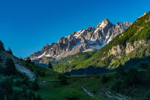 a view of a mountain range with a green field at Chalet Les écrins Guillestre Vars Risoul Queyras in Guillestre