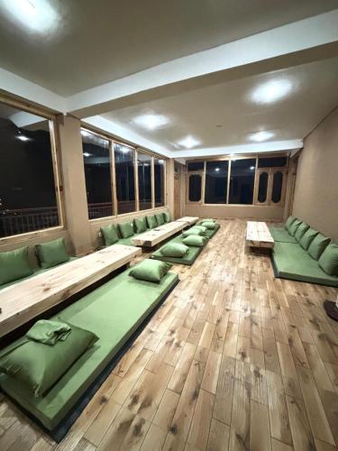 a room with green pillows on the floor at Mizuki Retreat and Cafe, Tirthan Valley in Gushaini