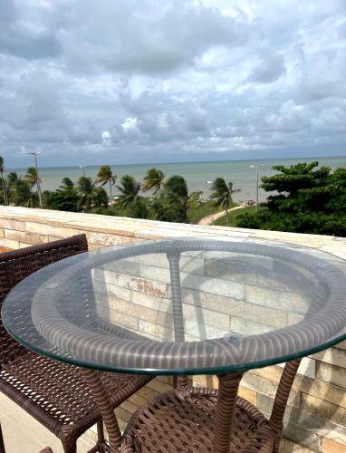 a glass table on a balcony with a view of the ocean at Imperial flat tambau Joao Pessoa in João Pessoa