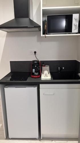 une cuisine avec un comptoir noir et un four micro-ondes dans l'établissement Le péronne-4, à Cambrai