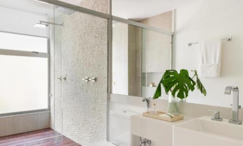 a white bathroom with a shower and a sink at Lofts Marambaia in Petrópolis