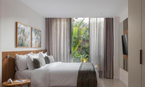 a bedroom with a large bed and a large window at Lofts Marambaia in Petrópolis