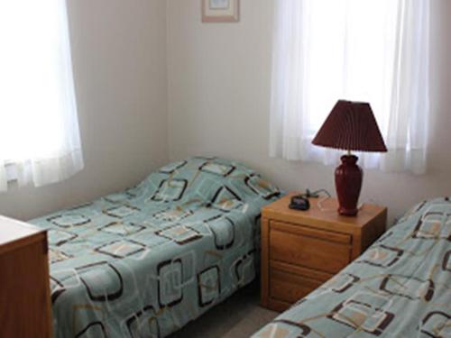 Un dormitorio con dos camas y una lámpara en una mesita de noche. en Ocean Block Internetwifi Deck Washer & Dryer Well-Maintained First Floor Unit Of An Ocean Block Duplex Great Location, Just One House Between, en Peahala Park