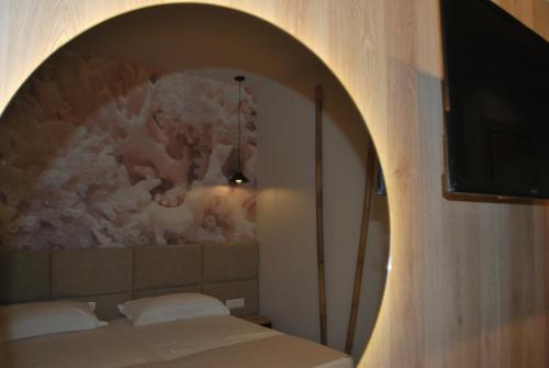a bedroom with a bed and a wall with a painting at Sofo Hotel Dhermi in Dhërmi
