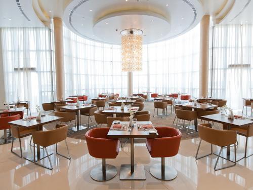 a restaurant with tables and chairs and a chandelier at Novotel Abu Dhabi Gate in Abu Dhabi