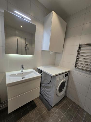 a bathroom with a washing machine and a sink at Centralt och modernt in Stockholm