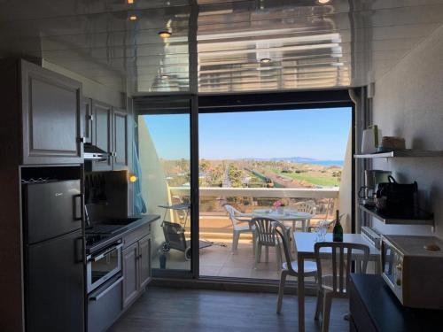 - une cuisine avec vue sur une terrasse dotée d'une table dans l'établissement Résidence Héliopolis Bâtiment Ab - Studio Cabine 2 pers- Héliopolis Bât. AB MAE-7211, au Cap d'Agde