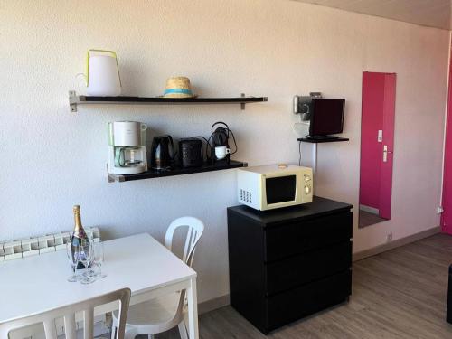 une cuisine avec une table et un four micro-ondes sur une armoire dans l'établissement Résidence Héliopolis Bâtiment Ab - Studio Cabine 2 pers- Héliopolis Bât. AB MAE-7211, au Cap d'Agde