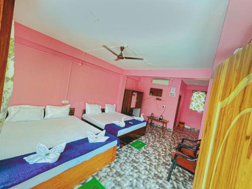 a bedroom with two beds and pink walls at ANIBESH HOTEL in Havelock Island