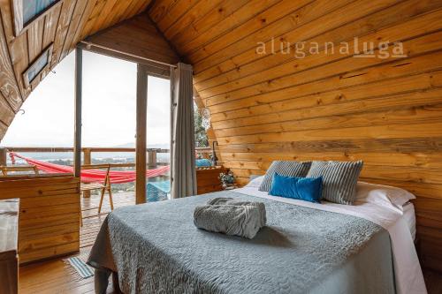 Un dormitorio con una cama en una cabaña de madera. en Cabaña Maldivas con vista - Pousada Sunset View, en Praia do Rosa
