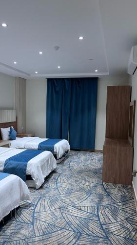 a hotel room with three beds and a carpet at مبيت دينا للشقق المخدومة - خميس مشيط - Mbit dina - Khamis Mushait in Khamis Mushayt