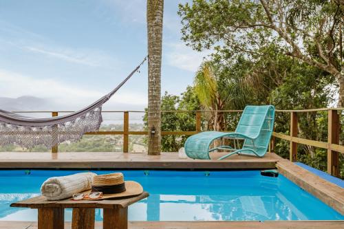 una hamaca y una silla junto a una piscina en Cabaña Maldivas con vista - Pousada Sunset View, en Praia do Rosa