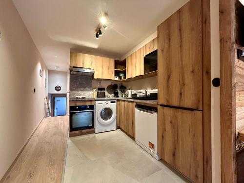 une cuisine avec des armoires en bois et une laveuse et une sécheuse dans l'établissement Homency - Résidence L'Expression D03, à L'Alpe-d'Huez