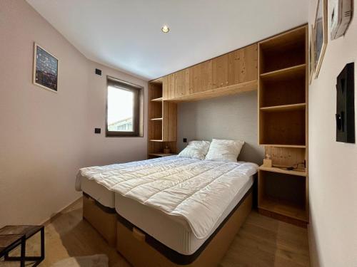 - une chambre avec un grand lit et des étagères en bois dans l'établissement Homency - Résidence L'Expression D03, à L'Alpe-d'Huez