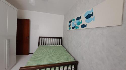 a room with a bed with a green bedspread on a wall at Quarto da Orla in Cabo Frio