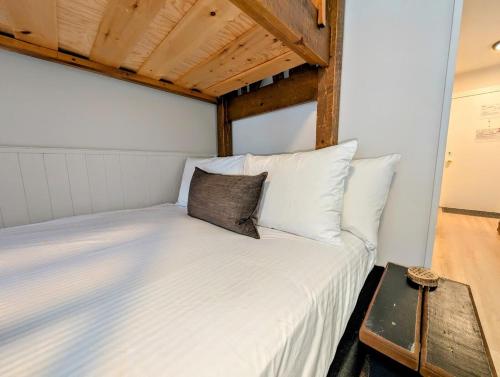 a bedroom with a white bed with a wooden ceiling at Purcell Condos by StayIn in Kimberley