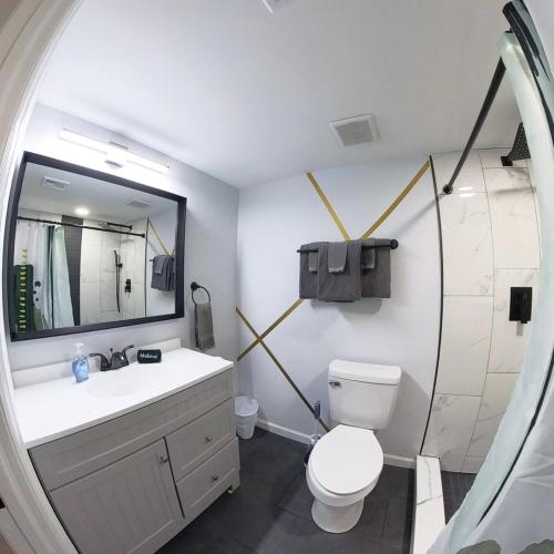 a bathroom with a toilet and a sink and a mirror at Posh Paradise -Modern Close to Casino & Water Park in Atlantic City