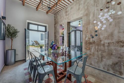 a dining room with a glass table and chairs at Casa Lila in Mérida