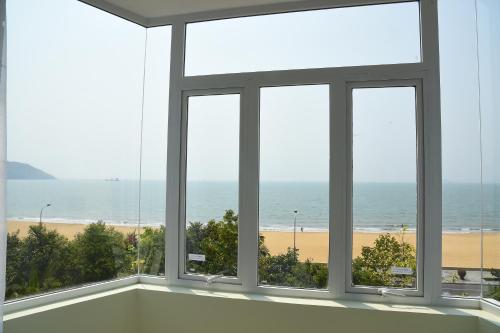 a room with windows looking out at the beach at Ly Ky Hotel in Quy Nhon