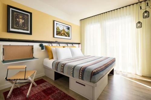 a bedroom with a bed and a chair and a window at Moxy Allentown Downtown in Allentown