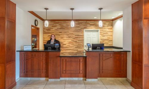 a woman sitting at a reception desk in a lobby at Staybridge Suites Rocklin - Roseville Area by IHG in Rocklin