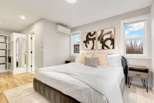 a white bedroom with a large bed and two windows at Modern Ballard Retreat Near Beach & Parks in Seattle