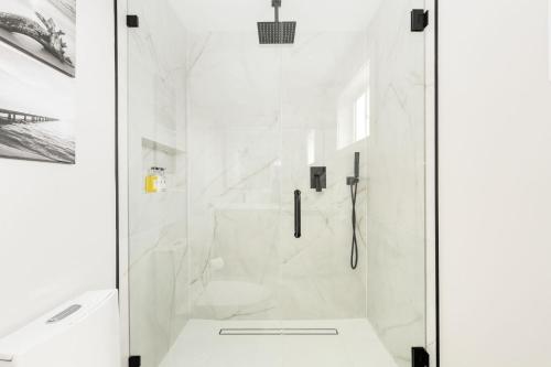 a white bathroom with a shower with a glass door at Modern Ballard Retreat Near Beach & Parks in Seattle