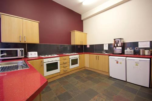 a large kitchen with wooden cabinets and white appliances at Albatross Hostel in Newcastle upon Tyne